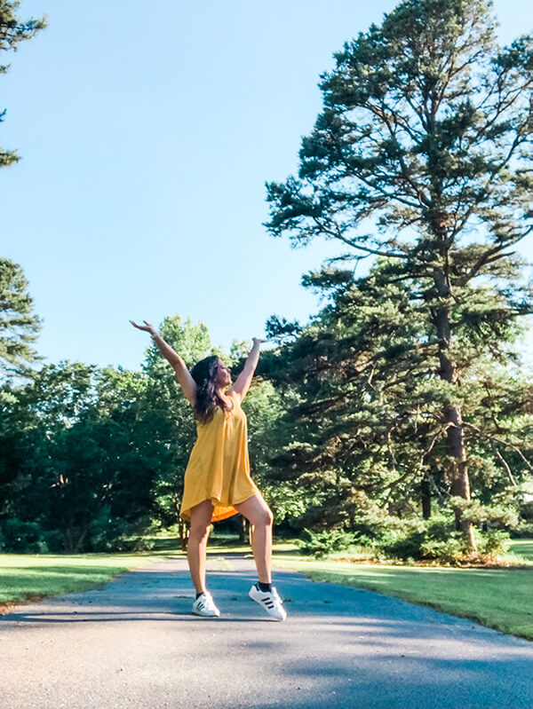 Girl wearing a yellow dress with class Adidas - with hands raised in the air in joy