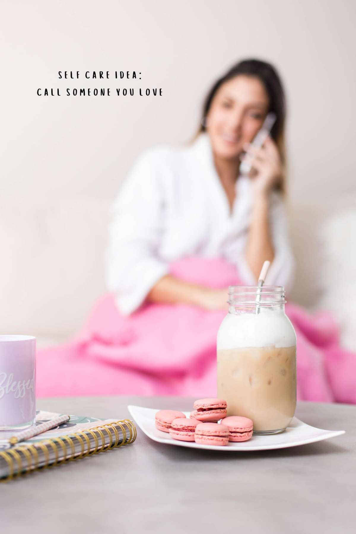 Picture shows a girl on a cell phone in the background. In the foreground, there's an iced coffee and some macarons.