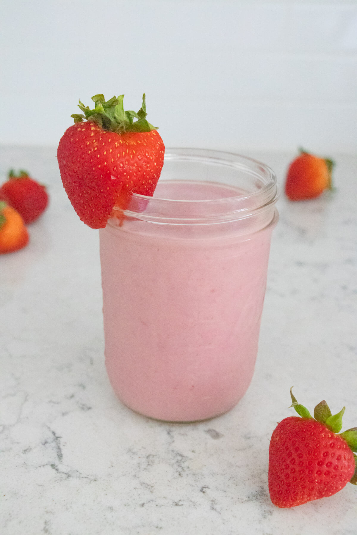 Strawberry smoothie with strawberries in the background