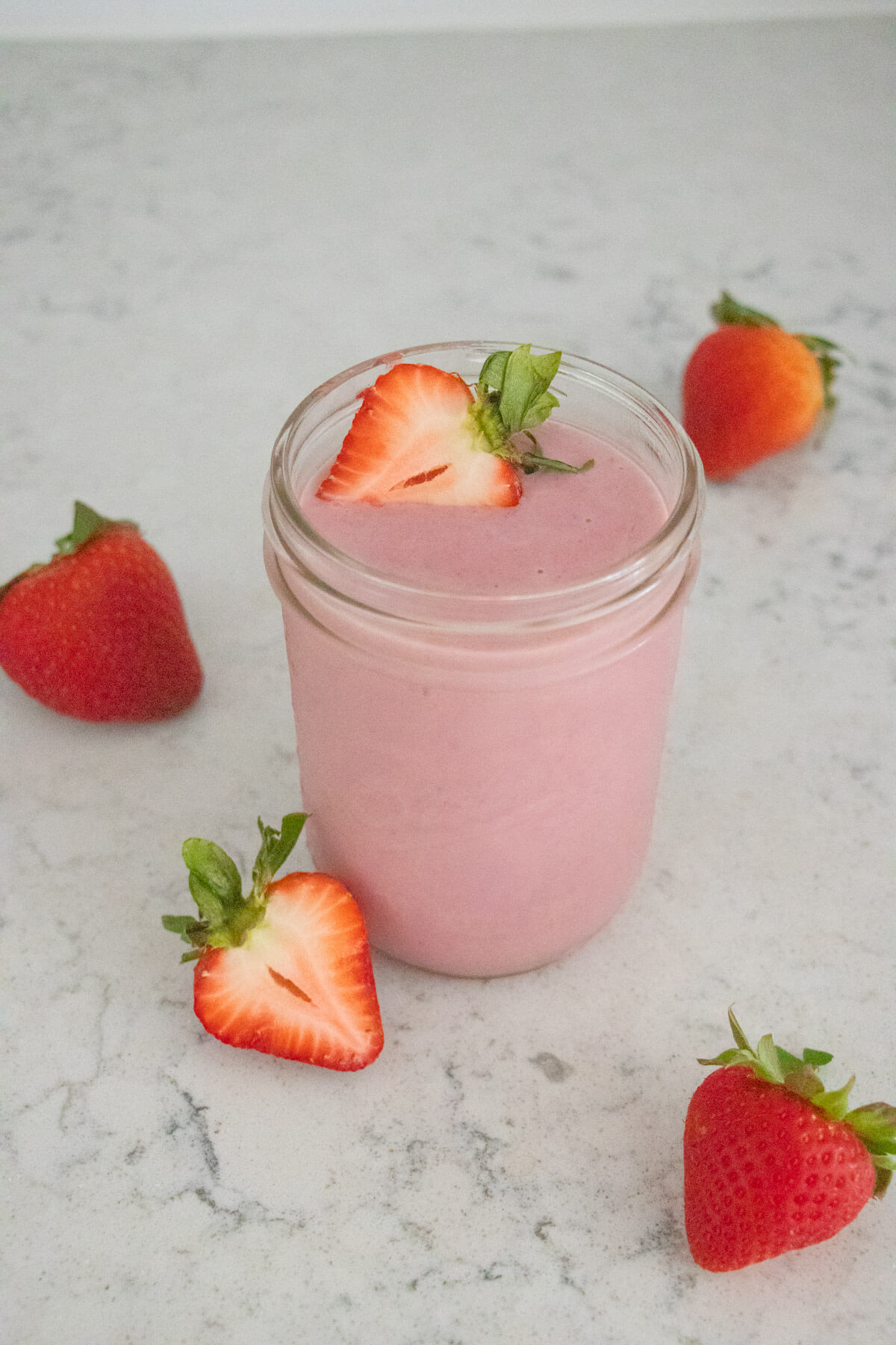 Strawberry smoothie with strawberries in the background