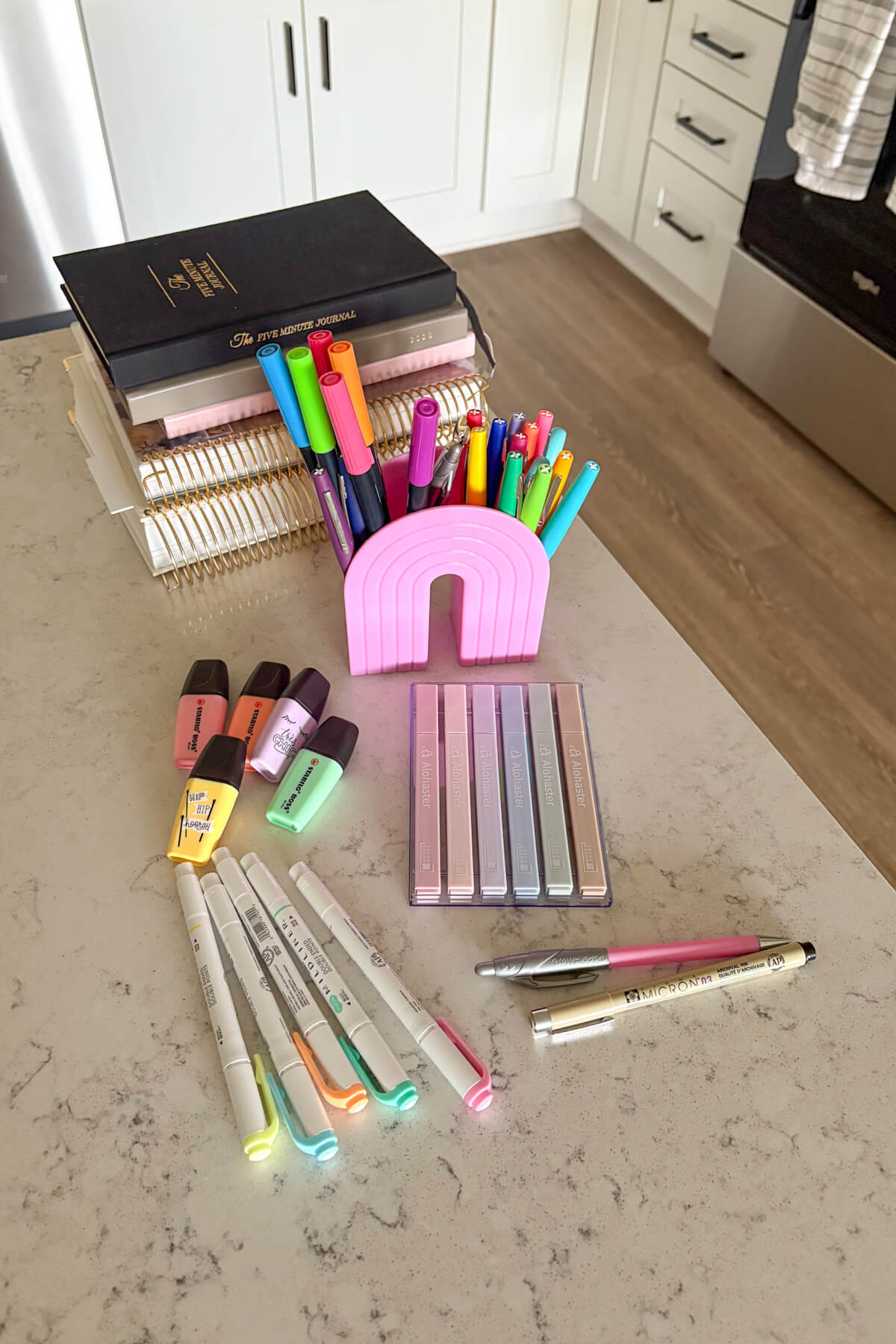 A stack of planners and journals plus pens, markers, and highlighters